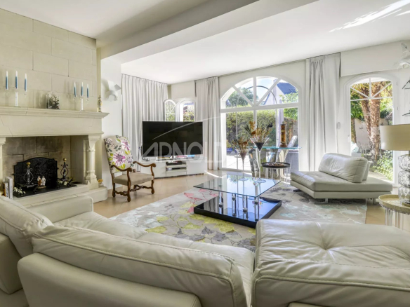 Salon lumineux avec cheminée et grandes fenêtres, mobilier moderne et décoration élégante.