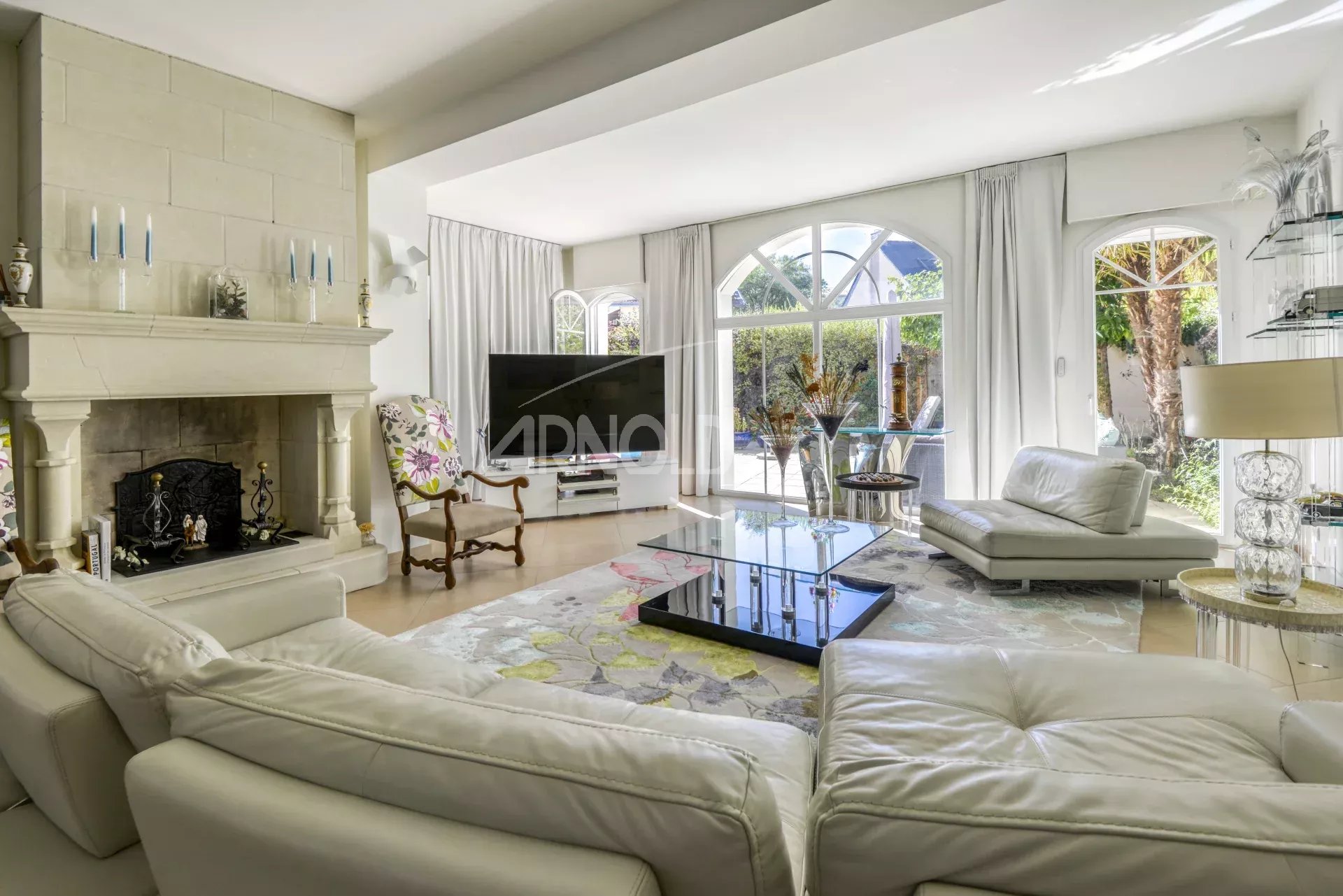 Salon lumineux avec cheminée et grandes fenêtres, mobilier moderne et décoration élégante.