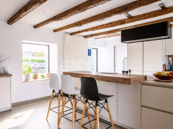 Modern kitchen with bar and high chairs, exposed beams, natural light.