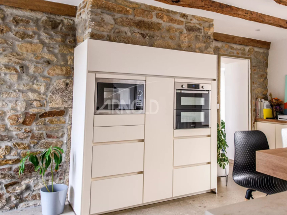 Modern kitchen with integrated appliances and stone walls in a contemporary farmhouse.