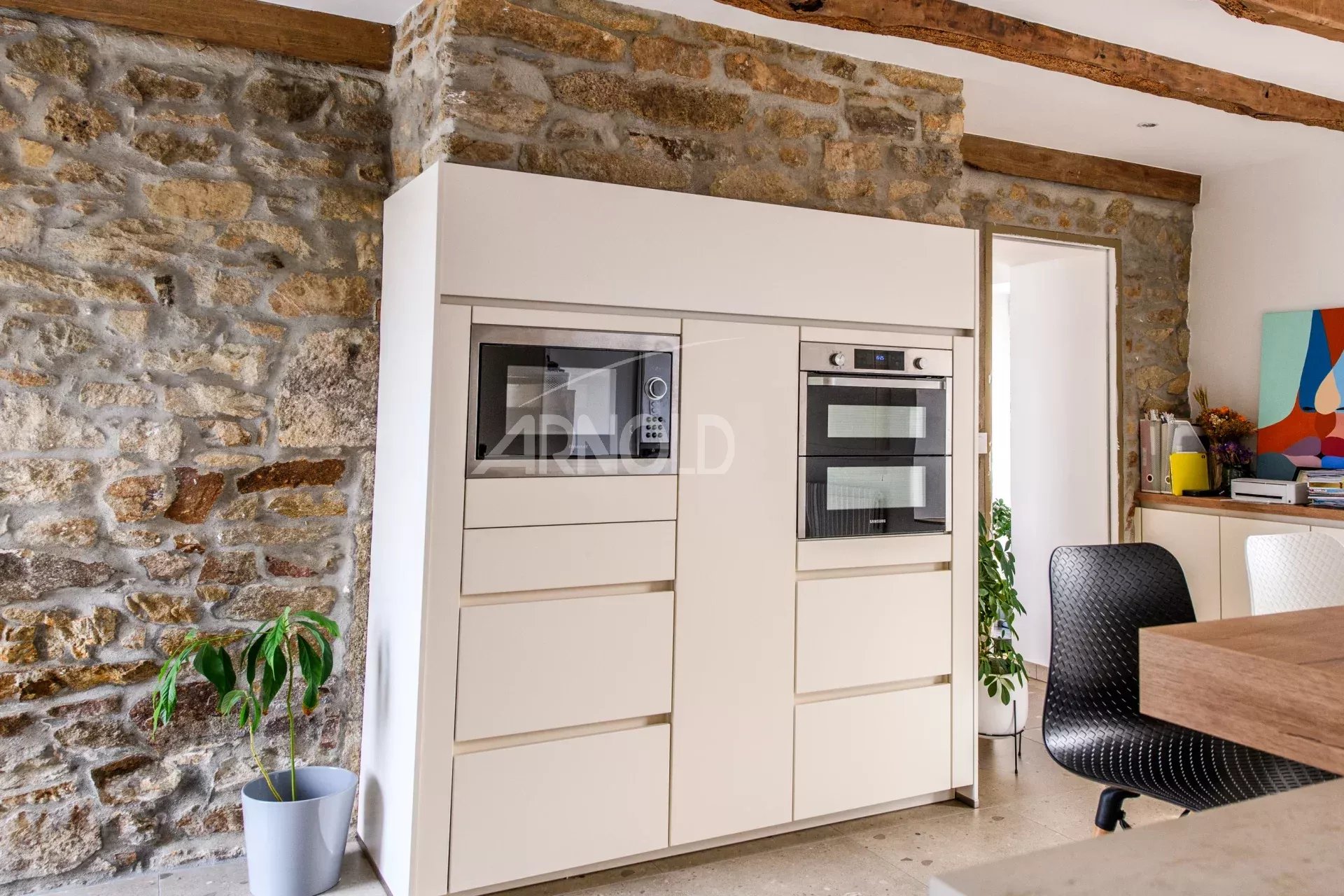 Kitchen of a contemporary farmhouse in Surzur Modern kitchen with integrated appliances and stone walls in a contemporary farmhouse.