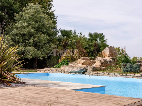Swimming pool surrounded by vegetation and rocks in a contemporary property in Surzur.