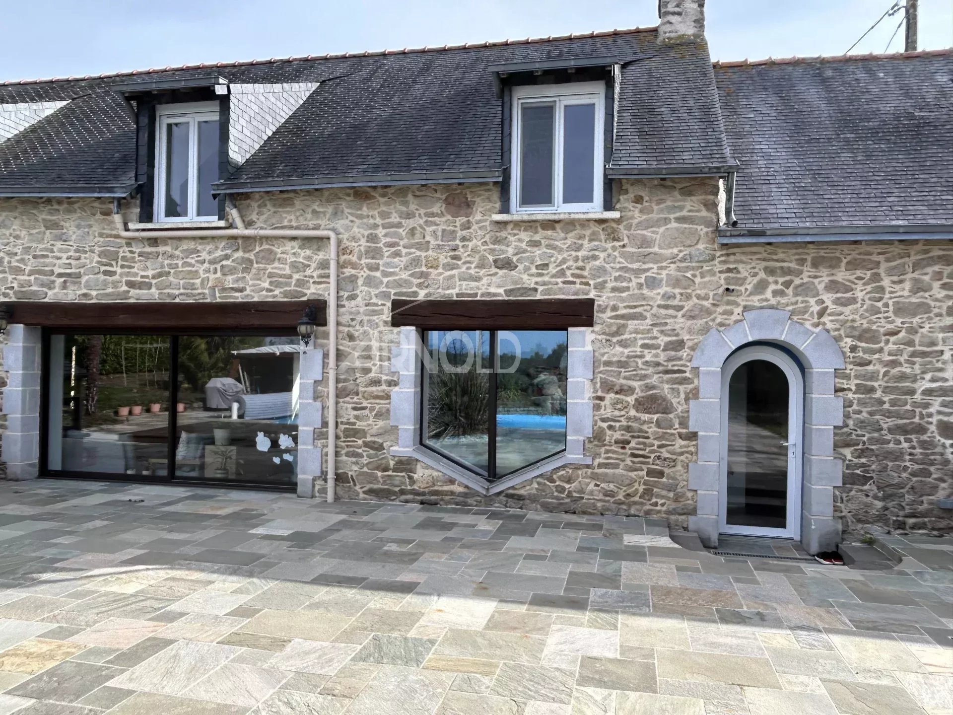 Contemporary farmhouse with swimming pool Contemporary stone farmhouse with large windows and swimming pool visible at the rear.