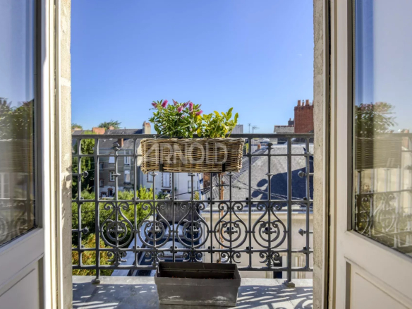 Balcony overlooking a private passage in Nantes, flowers and a terracotta pot on the balustrade.
