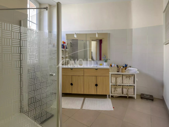 Modern bathroom with shower and wooden furniture, lit by natural light.