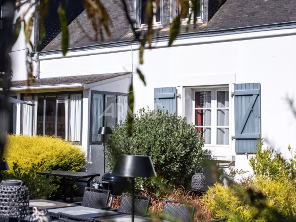 Maison de charme avec jardin à Belz, fenêtres à volets bleus et mobilier extérieur.