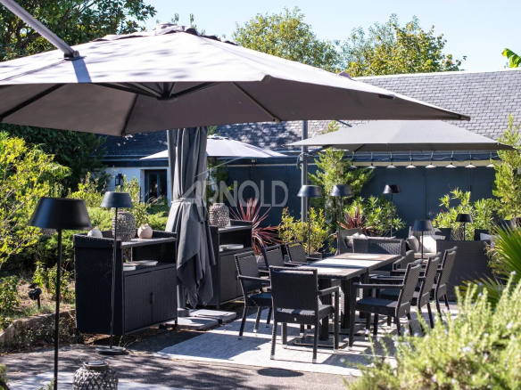 Terrasse de maison avec mobilier de jardin à Belz, entourée de verdure.