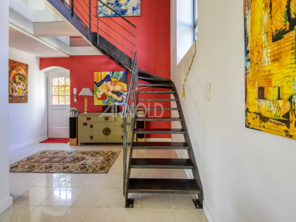 Intérieur d'une propriété avec un escalier moderne et des œuvres d'art aux murs.