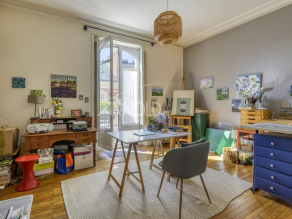 Intérieur d'un appartement T6 avec bureau et décoration artistique, lumière naturelle.