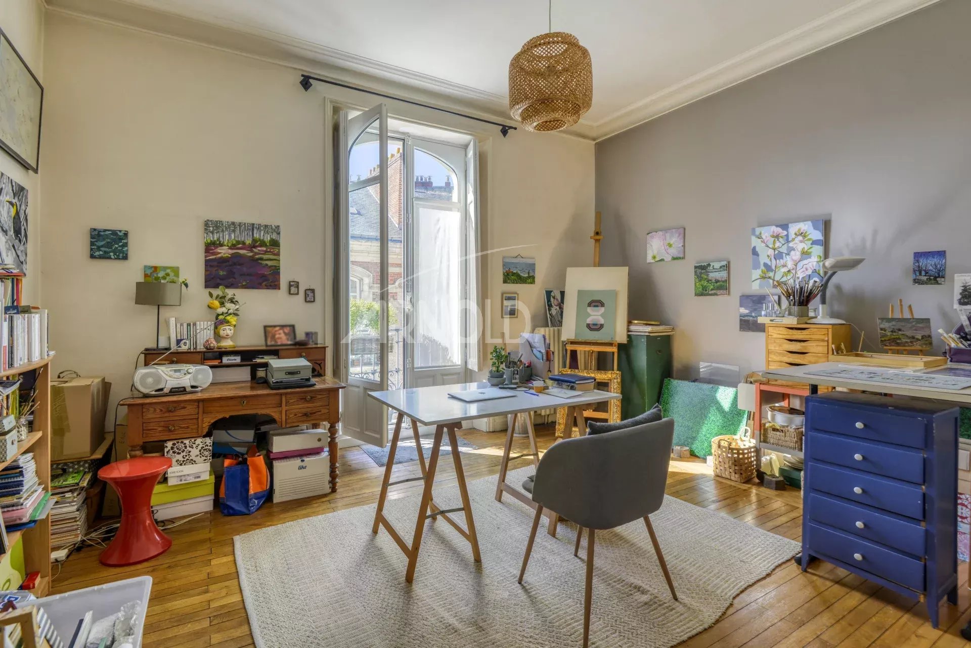 Intérieur d'un appartement T6 avec bureau et décoration artistique, lumière naturelle.