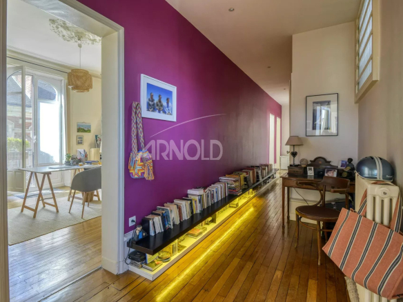 Intérieur d'un appartement T6 avec un couloir et des étagères à livres, murs violets.