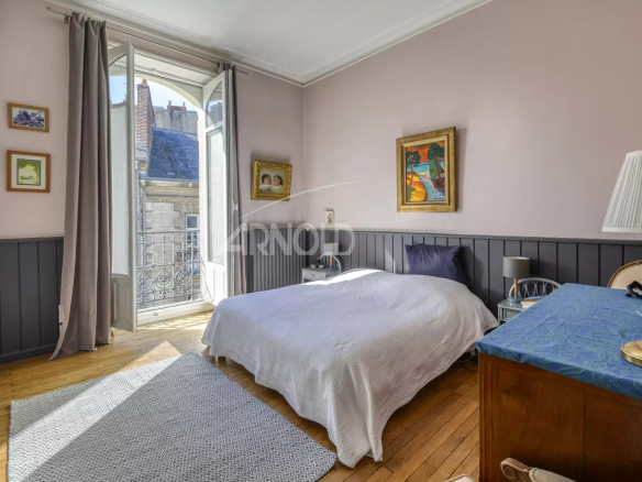Chambre d'appartement avec balcon, lumière naturelle, décor ancien à Nantes.