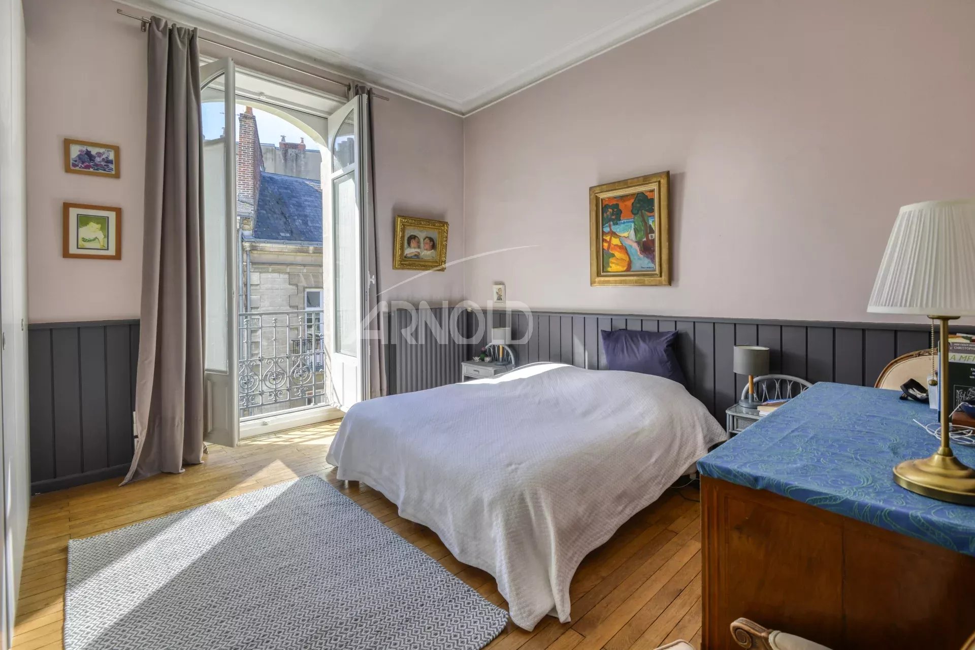 Chambre d'appartement avec balcon, lumière naturelle, décor ancien à Nantes.