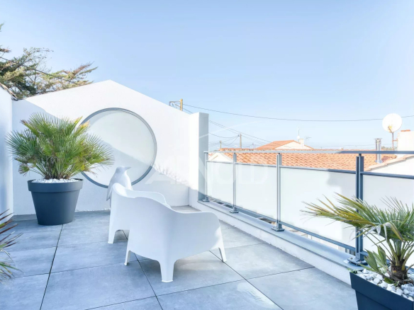 Terrasse d'une villa contemporaine avec chaises blanches et plantes, vue dégagée sur le quartier de La Chaume.