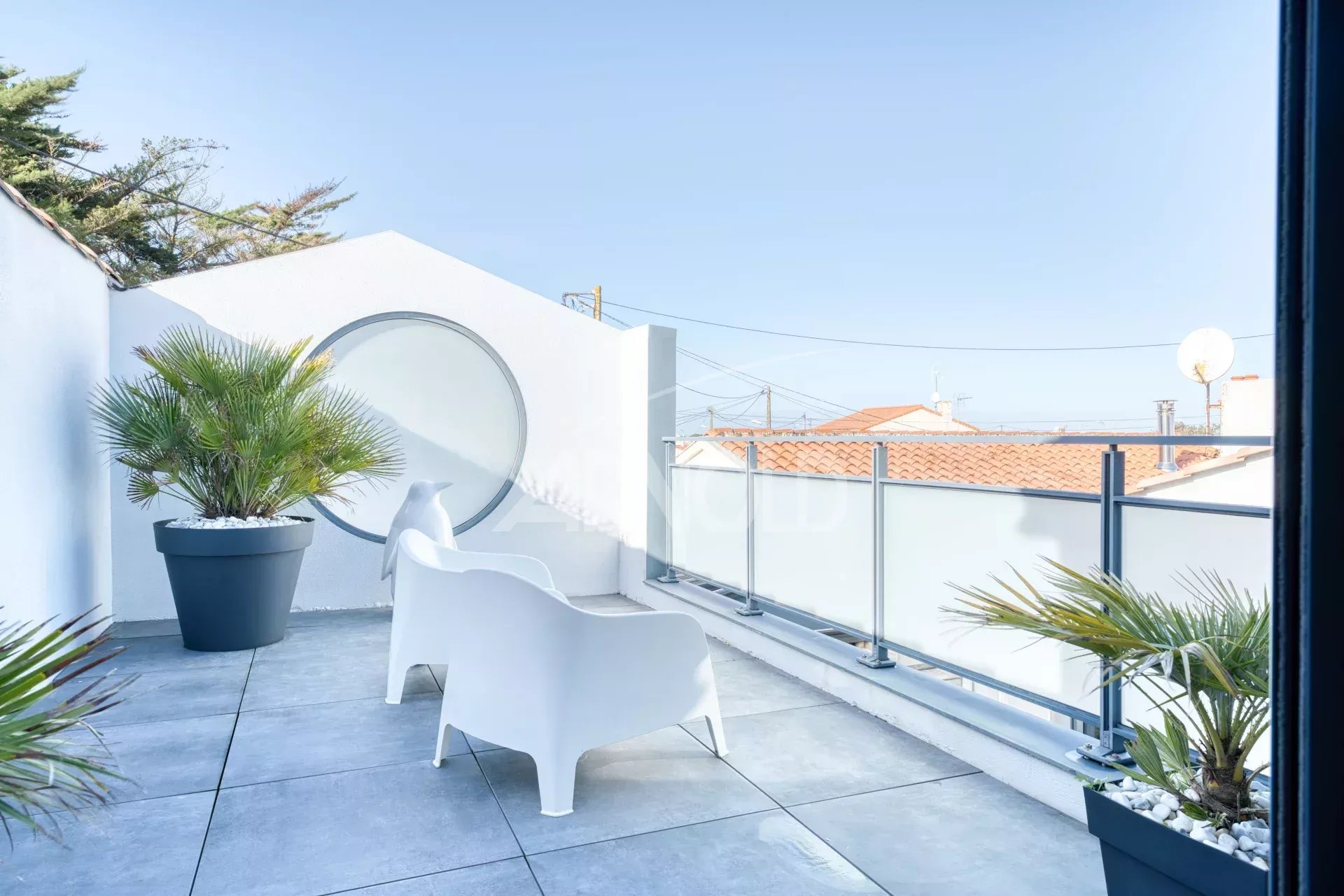 Terrasse de villa contemporaine à La Chaume Terrasse d'une villa contemporaine avec chaises blanches et plantes, vue dégagée sur le quartier de La Chaume.