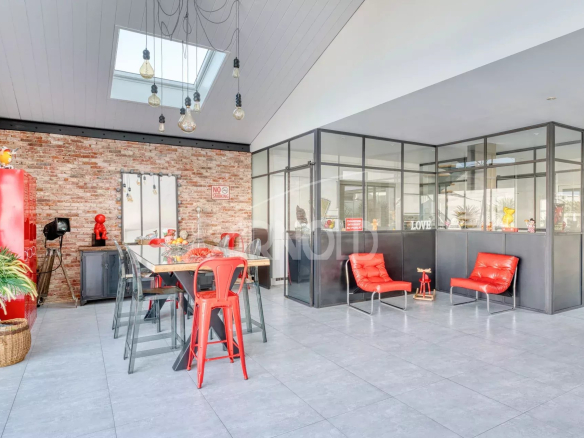 Intérieur d'une villa contemporaine avec salle à manger et coin salon, murs en briques apparentes.