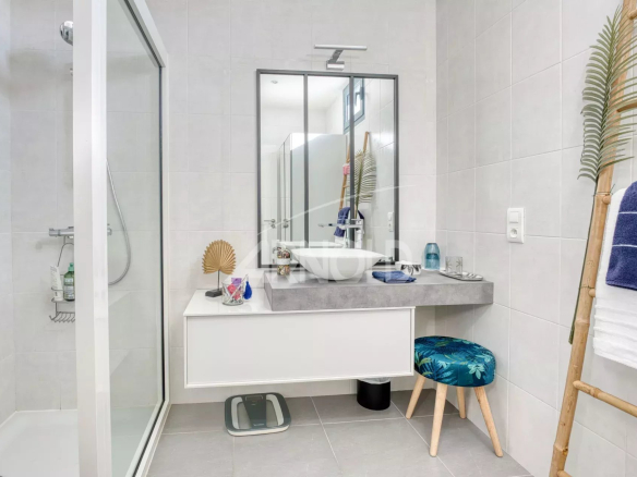 Salle de bain moderne avec douche, lavabo et miroir dans une villa contemporaine.