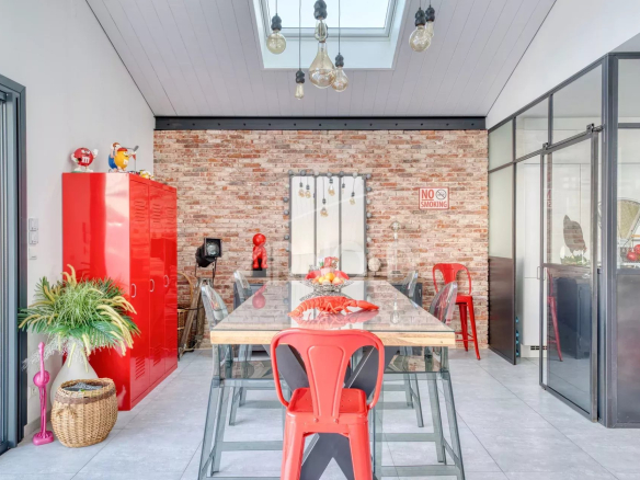 Intérieur d'une villa contemporaine avec une grande table et des chaises rouges, éclairage moderne.