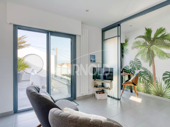 Intérieur d'une villa contemporaine avec un coin salon et des plantes décoratives.