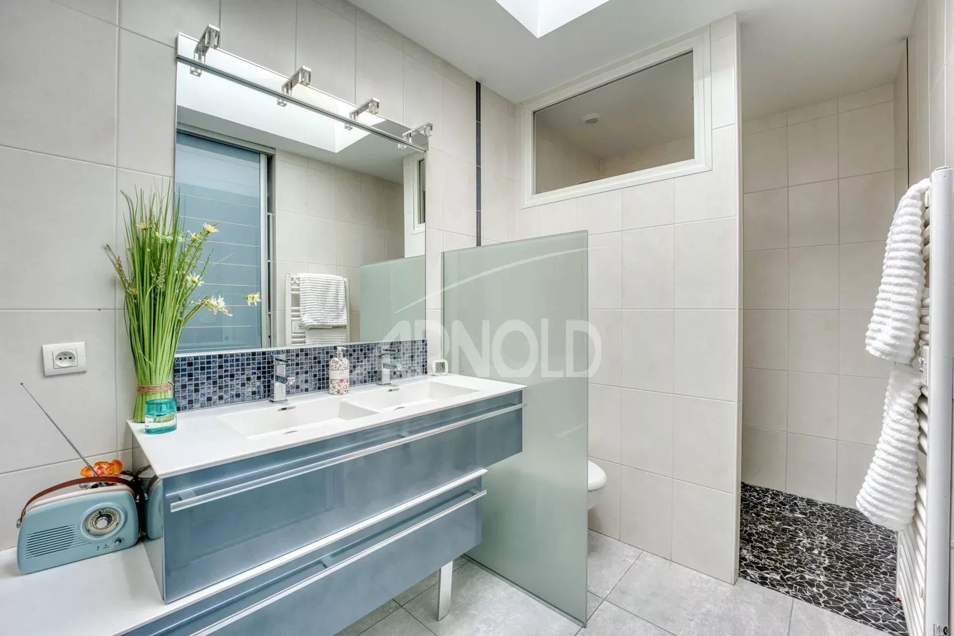 Salle de bains contemporaine Salle de bains moderne avec double vasque et douche, décorée de carrelage clair.