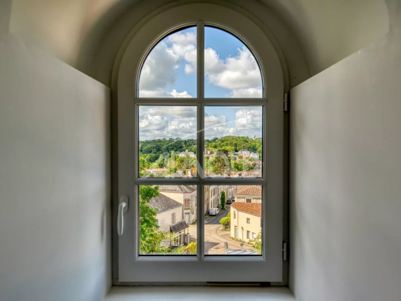 View from a window of the Exceptional Priory in Rocheservière, showing a green landscape and buildings.