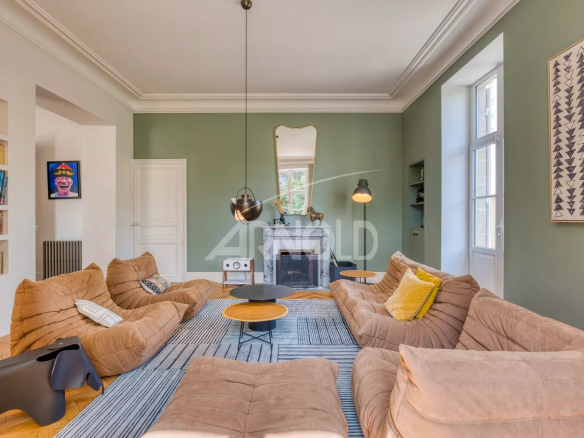 Interior of a spacious living room with beige fabric sofas and green walls, modern lighting.
