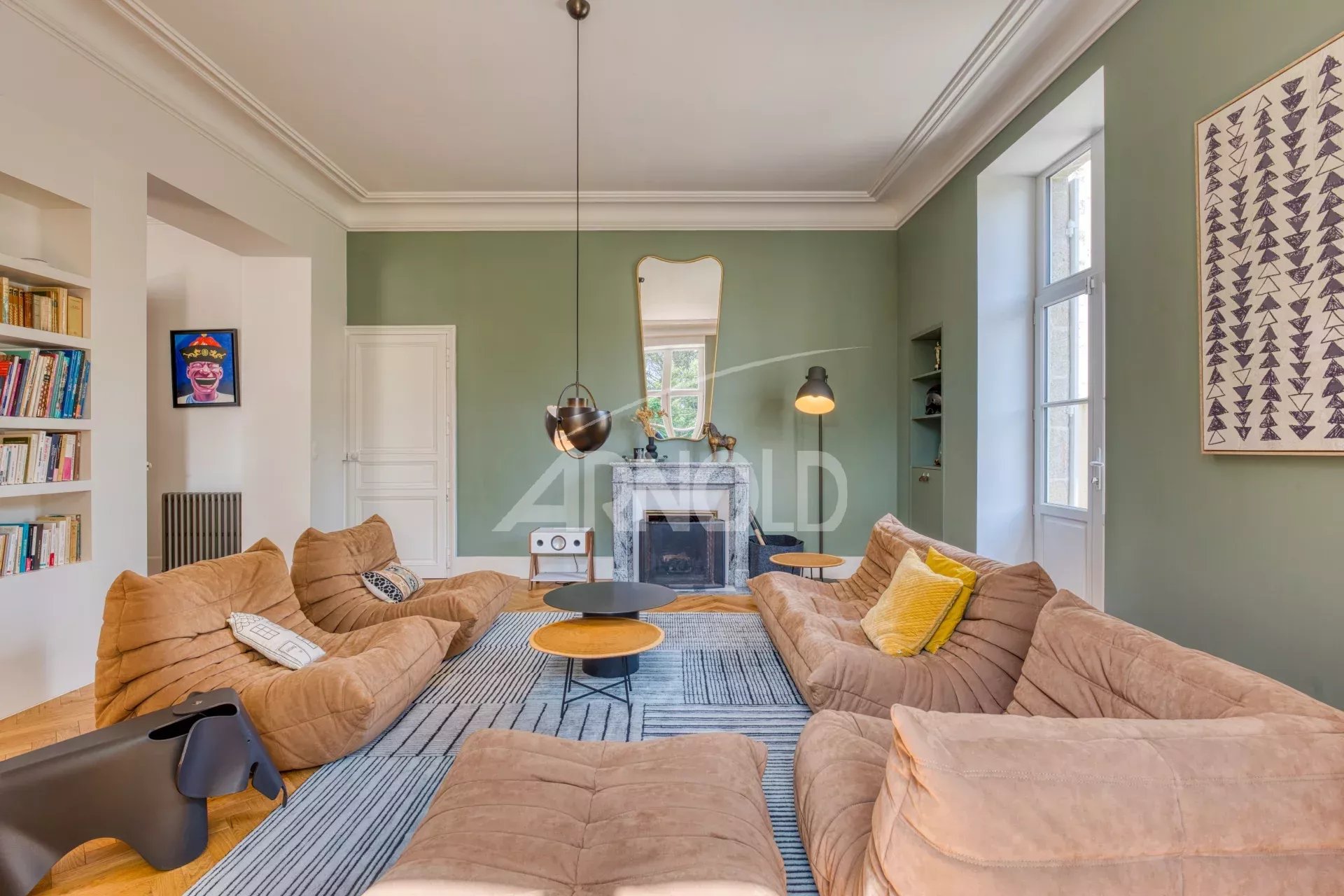 Interior of a spacious living room with beige fabric sofas and green walls, modern lighting.
