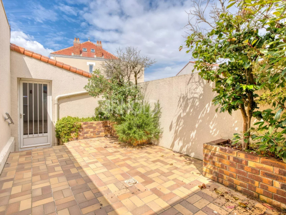 Paved terrace with plants, boundary wall, and front door in Saint-Gilles-Croix-de-Vie.