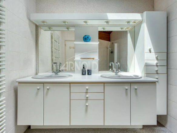 Modern bathroom with double sink and illuminated mirror.