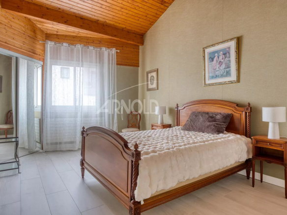 Spacious room with wooden bed and warm decor, natural light in Saint-Gilles-Croix-de-Vie.