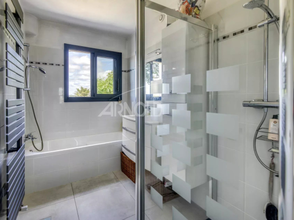 Modern bathroom with shower and bathtub, windows letting in light.