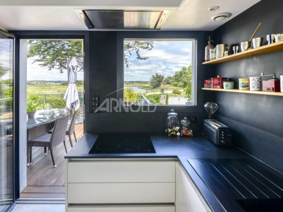 Modern kitchen with views of the tidal flat and nature, windows opening onto an outdoor space.