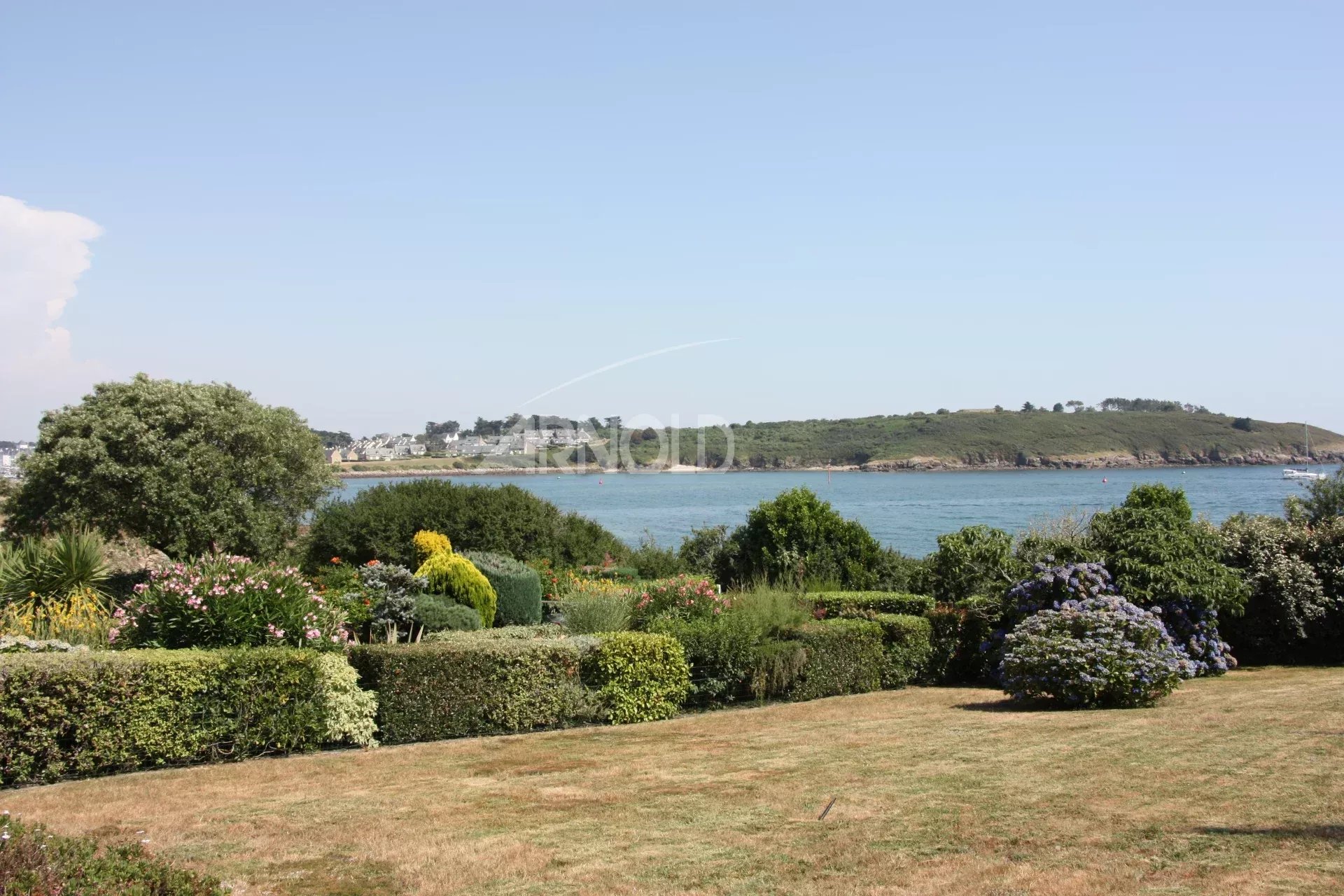 Vue sur l’océan à Arzon Vue panoramique sur l'océan et la plage depuis un jardin paysagé à Arzon.
