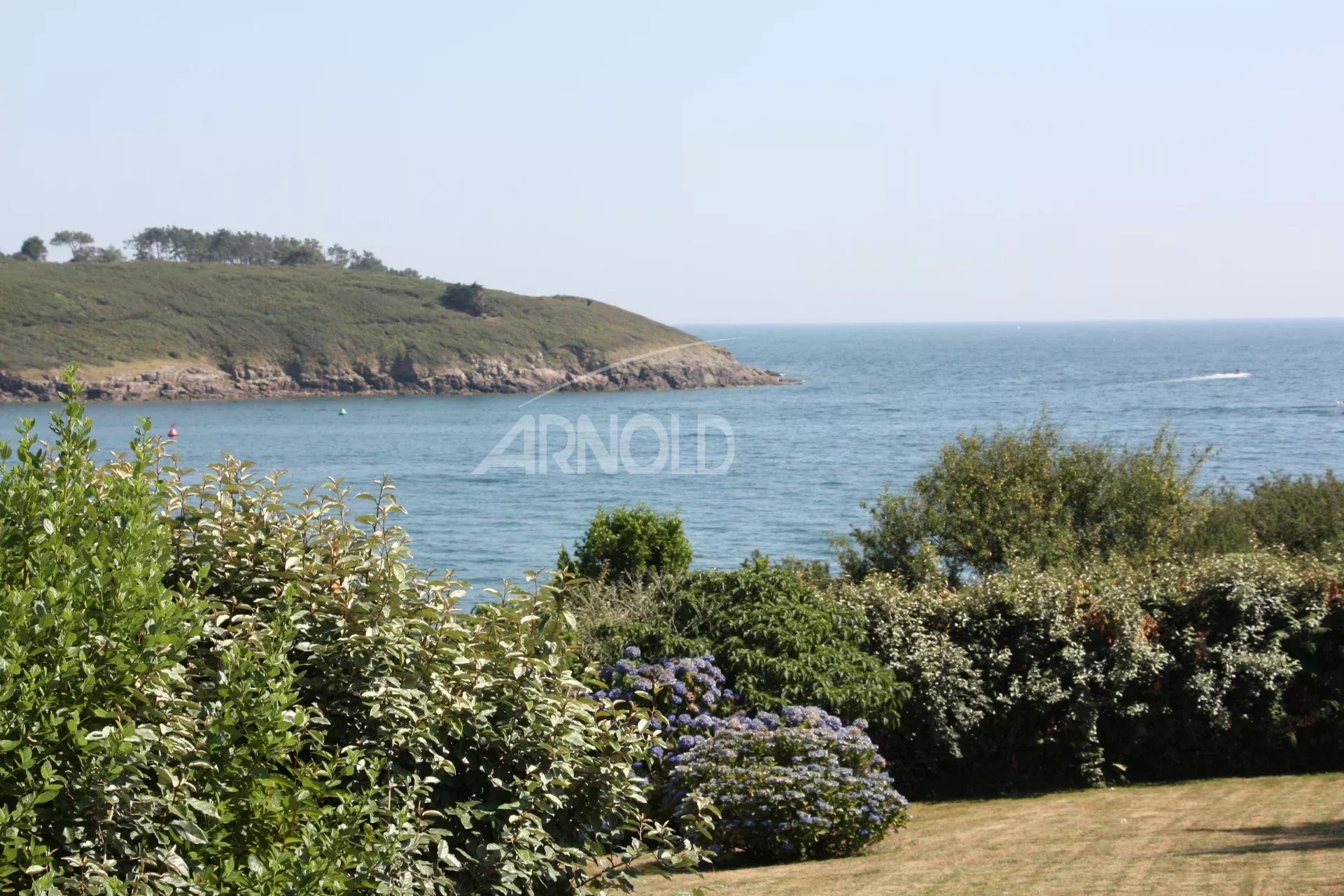 Vue sur l’océan à Arzon Vue panoramique sur l'océan et la plage depuis un jardin paysagé à Arzon.