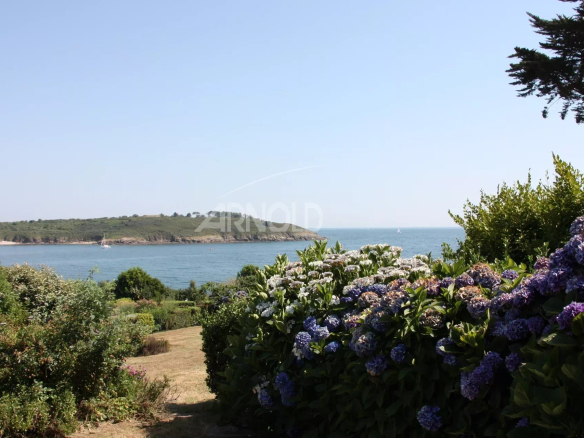 Vue panoramique sur l'océan et la plage depuis un jardin paysagé à Arzon.