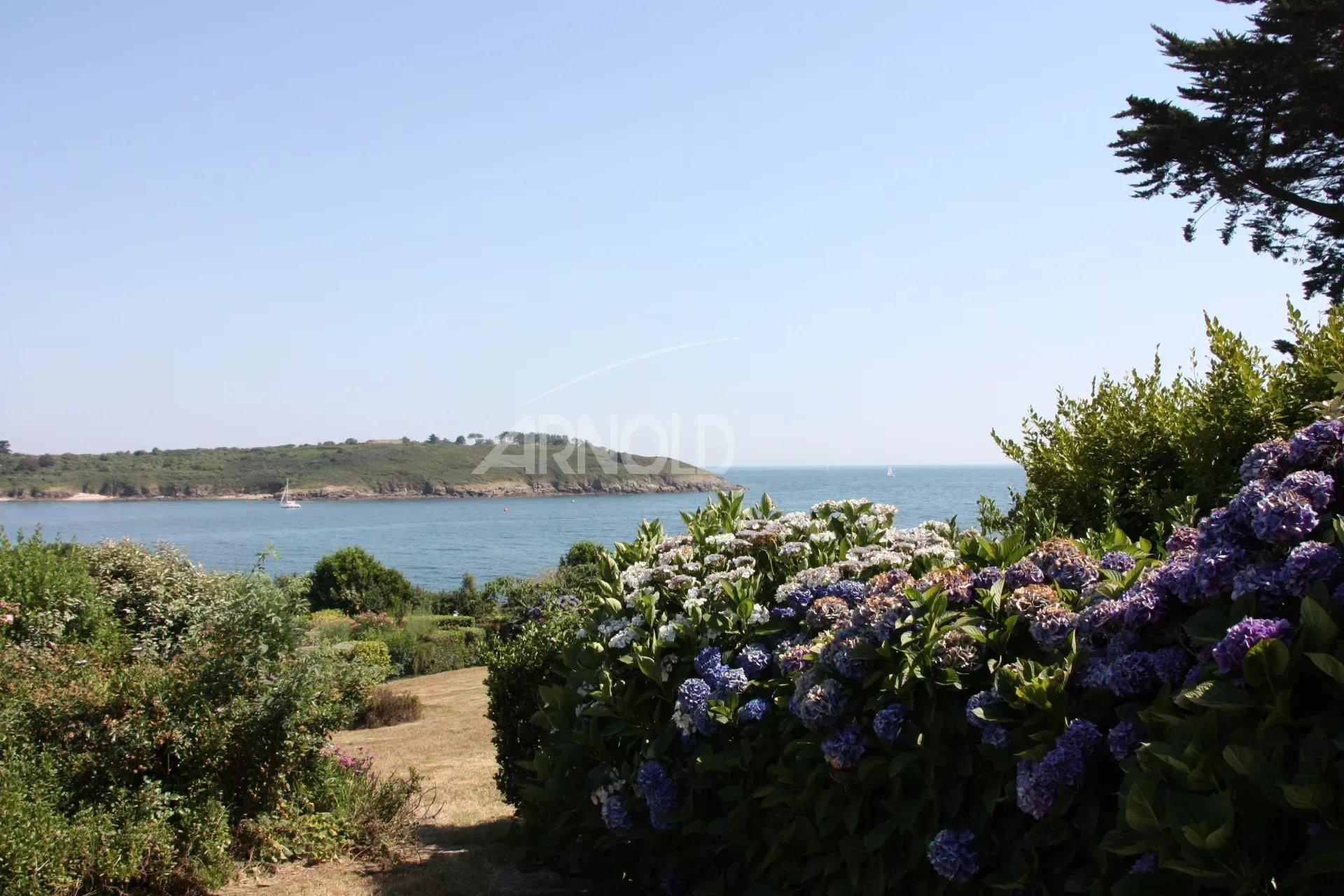 Vue sur l’océan à Arzon Vue panoramique sur l'océan et la plage depuis un jardin paysagé à Arzon.