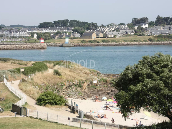 Vue panoramique sur la plage et l'océan à Port Navalo, Arzon, avec des personnes sur le sable.