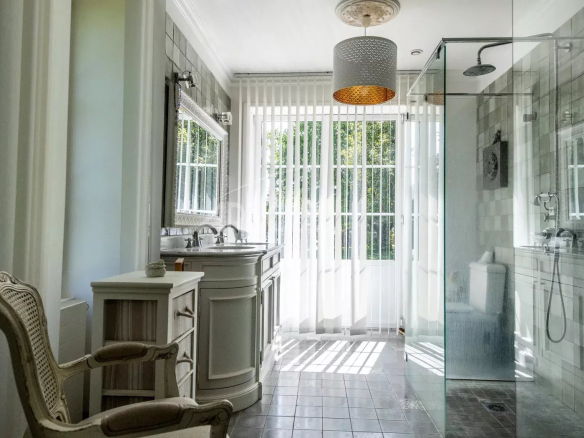 Salle de bain lumineuse avec douche vitrée et meuble lavabo élégant.
