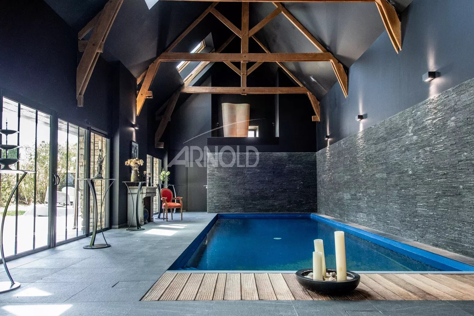 Intérieur d’une propriété de charme Intérieur d'une propriété avec piscine, poutres apparentes et murs en pierre, éclairage moderne.