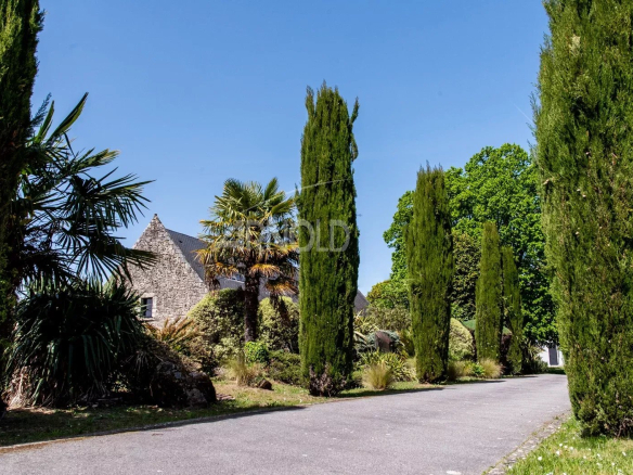 Entrée d'une propriété bordée d'arbres et de plantes, à proximité de Vannes.