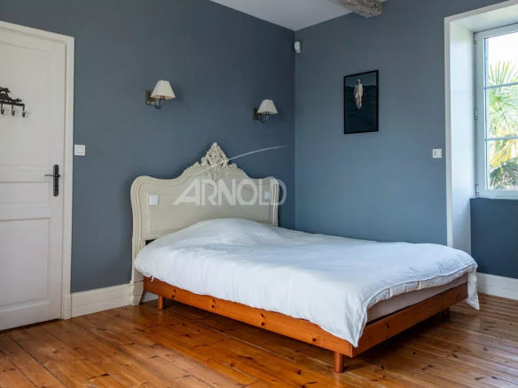 Chambre d'une propriété rénovée avec un lit en bois et des murs gris à Saint-Avé près de Vannes.