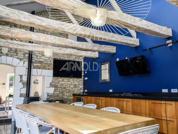 Intérieur d'une propriété rénovée avec poutres apparentes et table en bois dans une cuisine moderne.