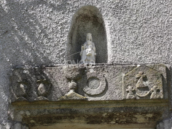 Sculpture en pierre représentant une figure religieuse sur un mur en extérieur.