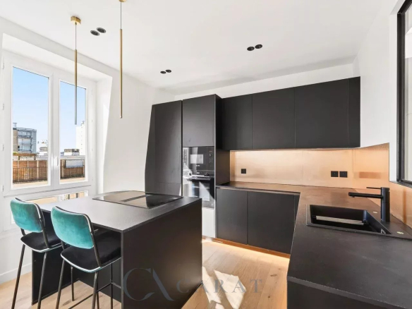 Modern black kitchen with copper backsplash, island cooktop, and teal-bar stools by a large window overlooking the city.