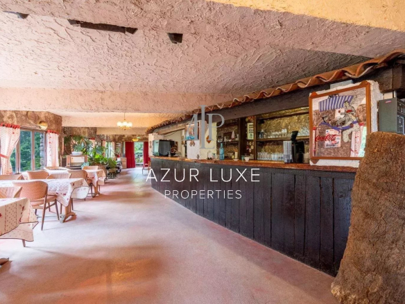 Interior of a former hotel-restaurant with wooden tables and bar, warm atmosphere.