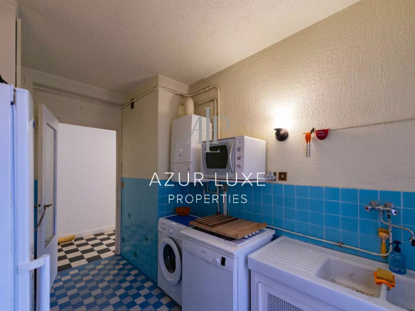 Kitchen of an apartment to be renovated with blue tiles and visible appliances.