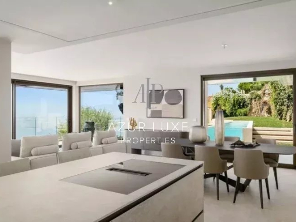 Intérieur moderne d'une villa avec vue sur la mer, salon et salle à manger.
