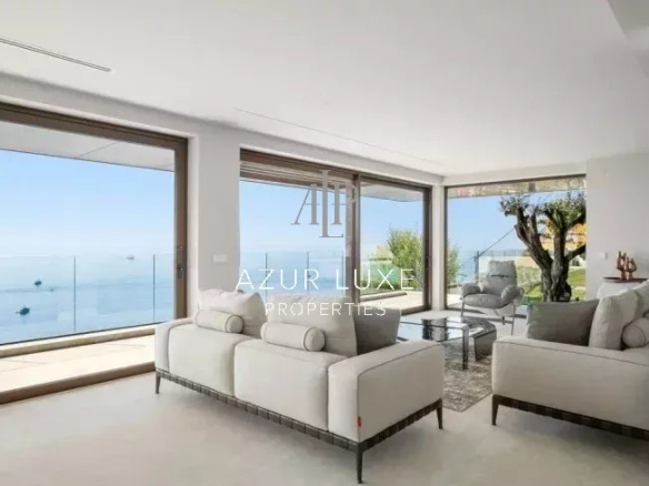 Intérieur d'une villa moderne avec vue mer, salon lumineux et mobilier contemporain.