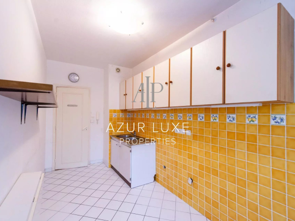 Kitchen of an apartment to be renovated with yellow tiles and white furniture, Beaulieu-sur-Mer.