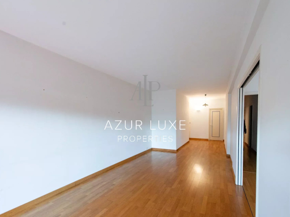 Interior of an empty apartment with a wooden floor, white walls and natural light.